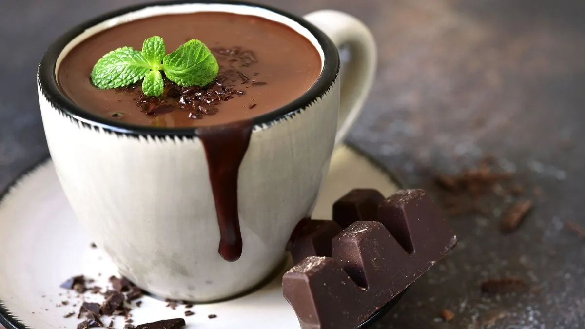 A steaming mug of hot chocolate topped with whipped cream and chocolate shavings.