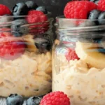 A jar of creamy overnight oats topped with fresh fruit and nuts.