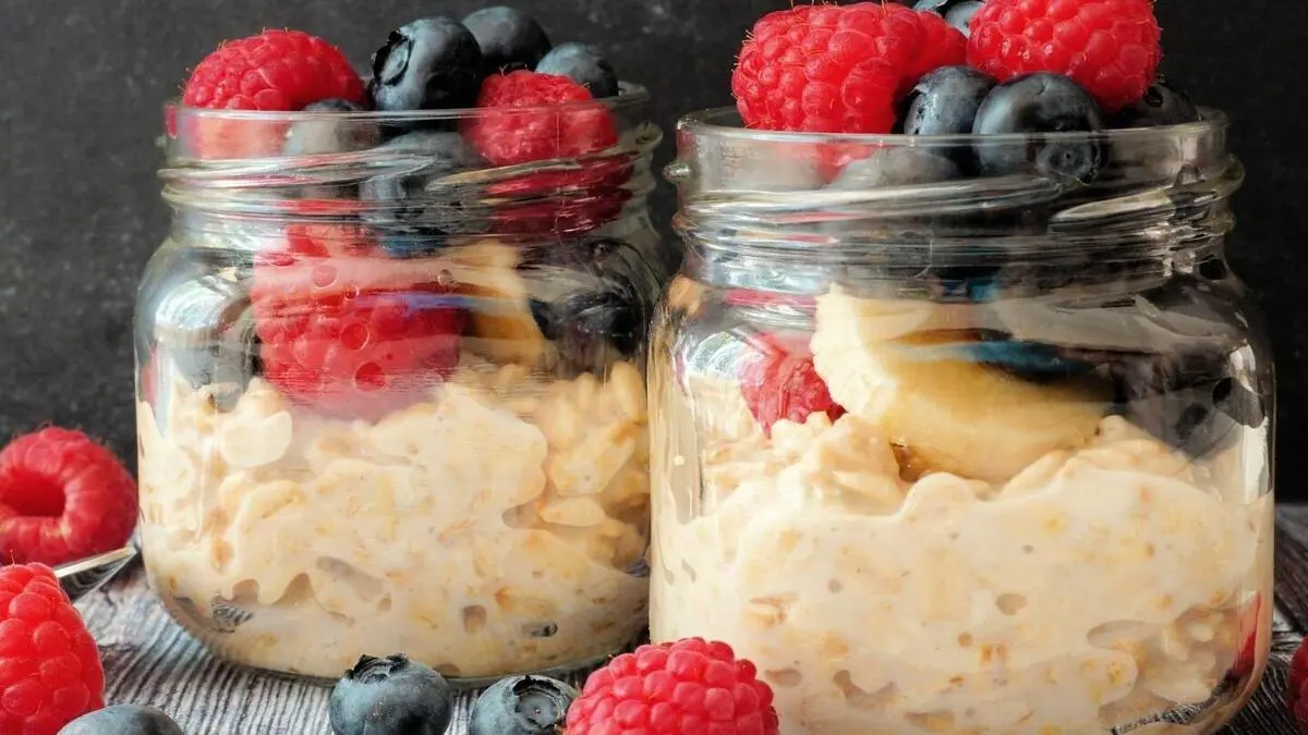 A jar of creamy overnight oats topped with fresh fruit and nuts.