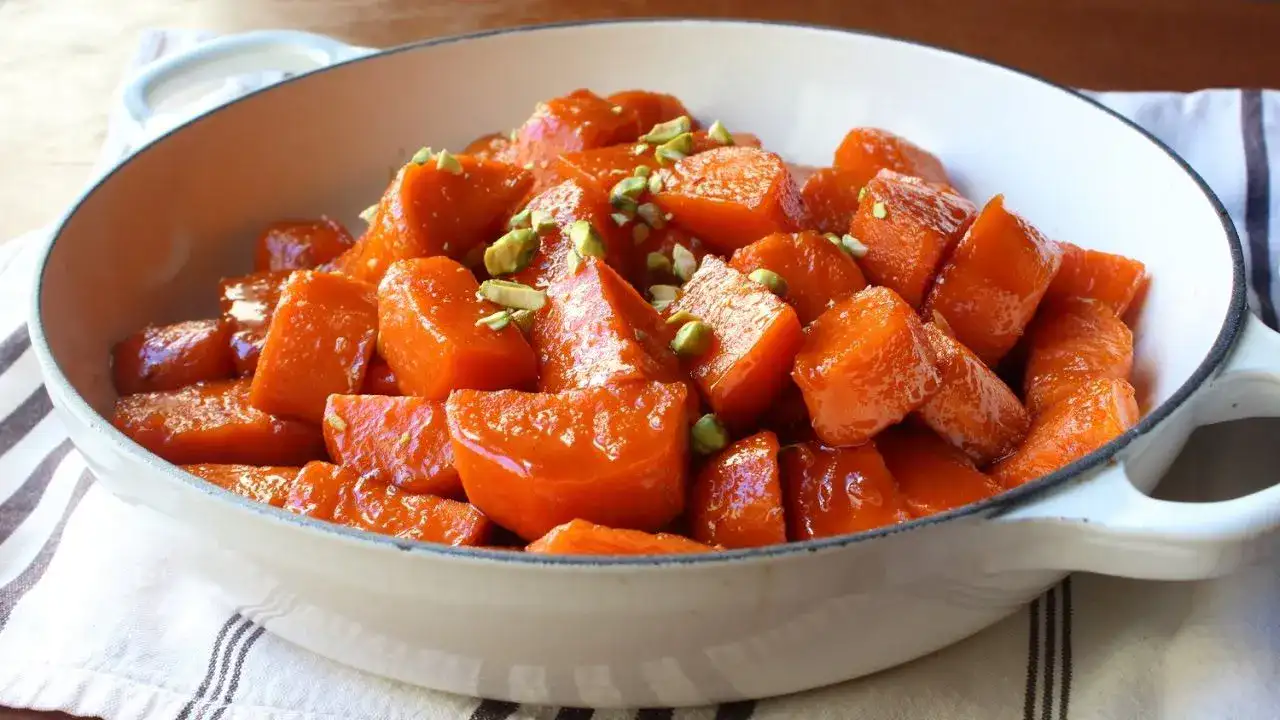 Bowl of candied yams topped with marshmallows and caramelized pecans