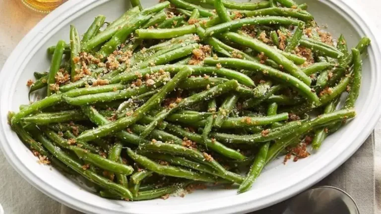 Vibrant green beans sautéed with garlic and topped with toasted almonds, served on a white plate