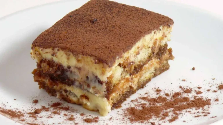 A beautifully layered Tiramisu dessert with coffee-soaked ladyfingers, creamy mascarpone, and a dusting of cocoa powder, served in a glass dish