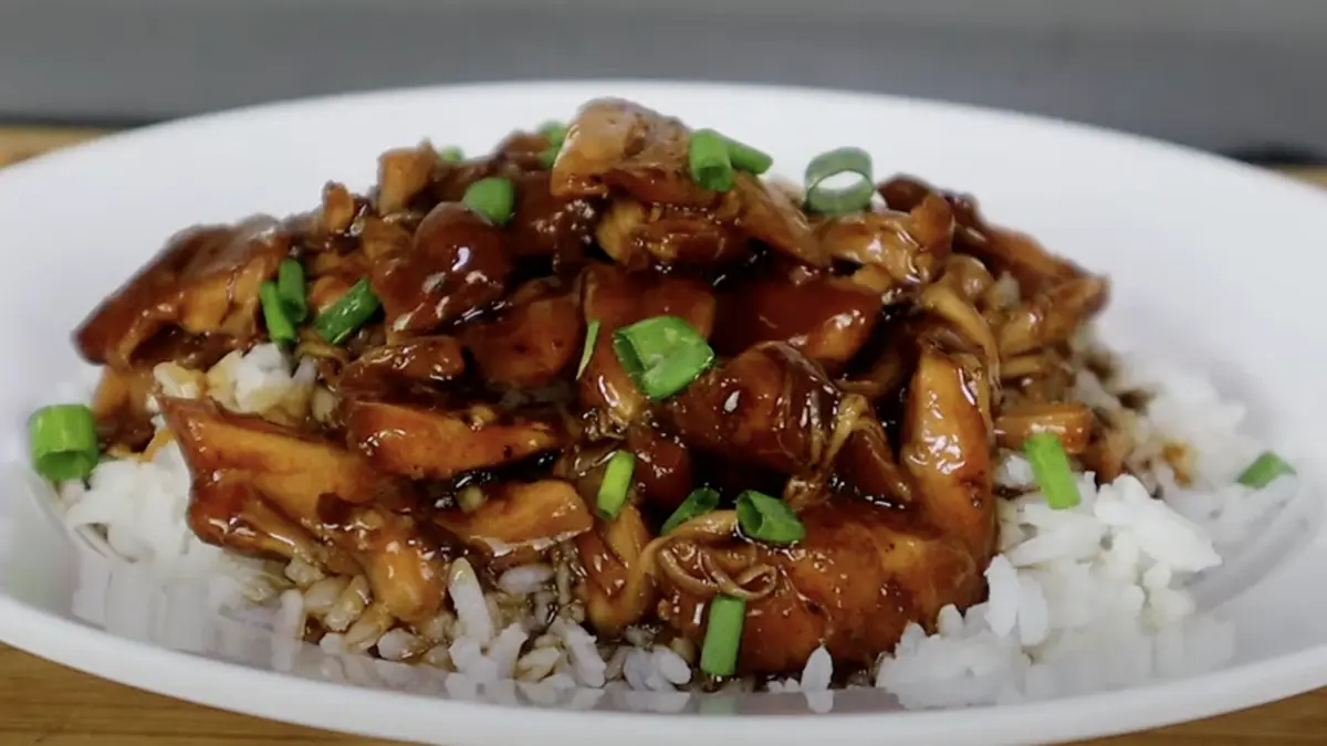 Delicious Bourbon chicken served over rice with a glossy glaze and garnished with green onions.