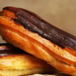 Delicious chocolate éclairs filled with rich chocolate pastry cream and topped with a glossy chocolate glaze, arranged on a decorative plate