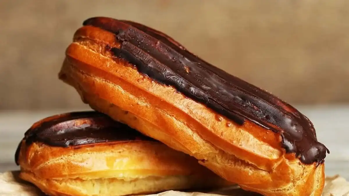 Delicious chocolate éclairs filled with rich chocolate pastry cream and topped with a glossy chocolate glaze, arranged on a decorative plate