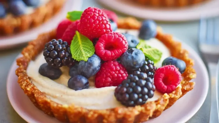 A beautiful fruit tart featuring a golden pastry crust filled with creamy custard and topped with a colorful array of fresh fruits, including strawberries, kiwi, and blueberries