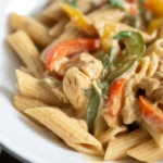 Creamy jerk chicken pasta with fresh vegetables served in a bowl