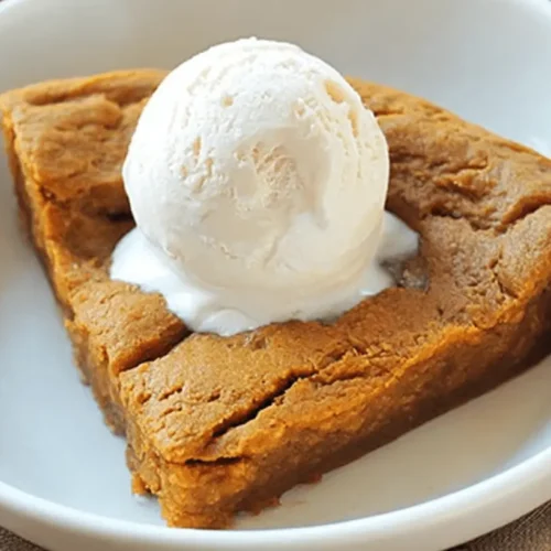 Delicious single serving of crustless pumpkin pie topped with melting vanilla ice cream in a white bowl.