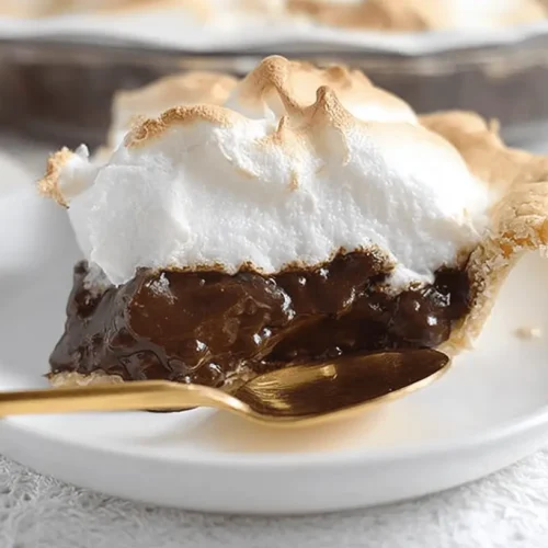 A beautifully presented slice of chocolate meringue pie with a fluffy toasted meringue and rich chocolate filling, ready to be enjoyed.